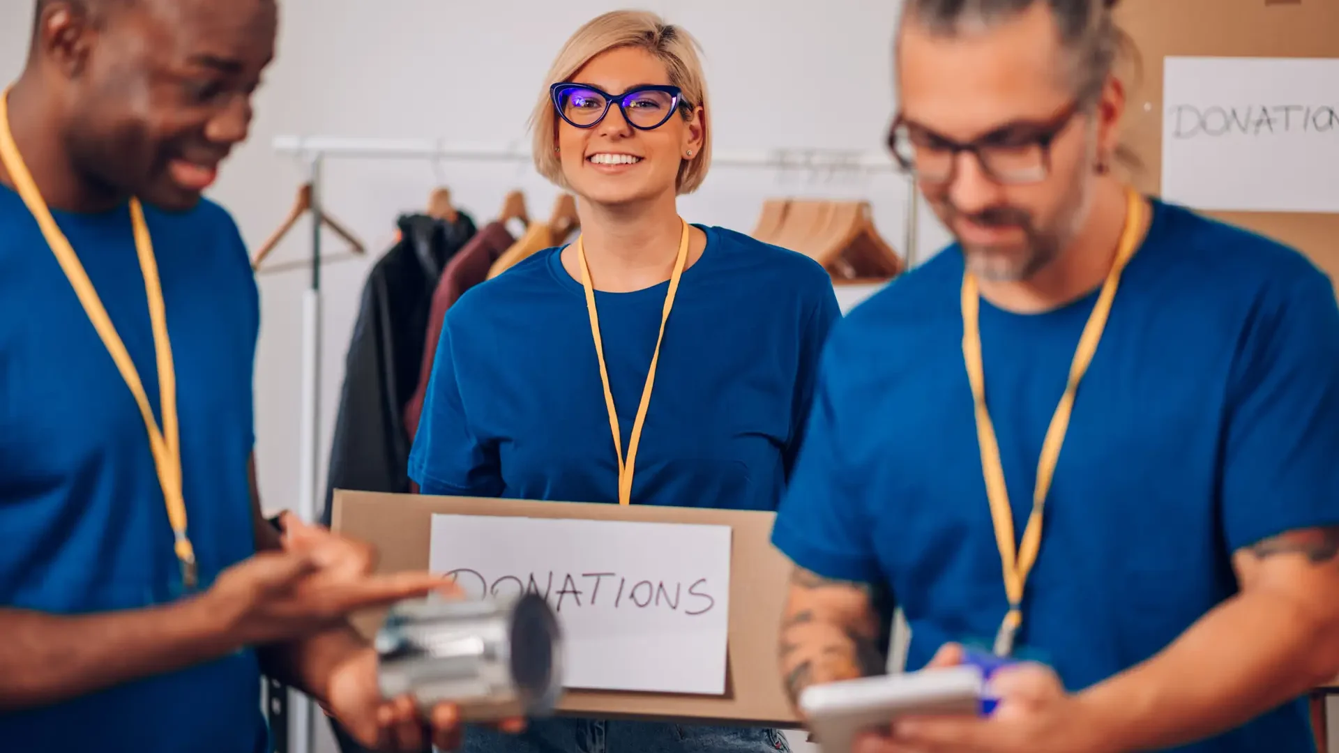 Diverse volunteers working in a charity donation center and packing clothes and food Group of multiracial volunteers helping people at charity center. Humanitarian aid concept. Focus on a blonde woman holding a donation box while working in homeless shelter. Copy space.
